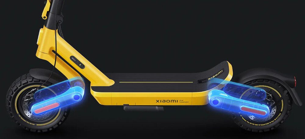 Żółta hulajnoga elektryczna z widocznymi dwoma amortyzatorami i napisem \'xiaomi\' na boku. Tło jest ciemne, co podkreśla kolor pojazdu.