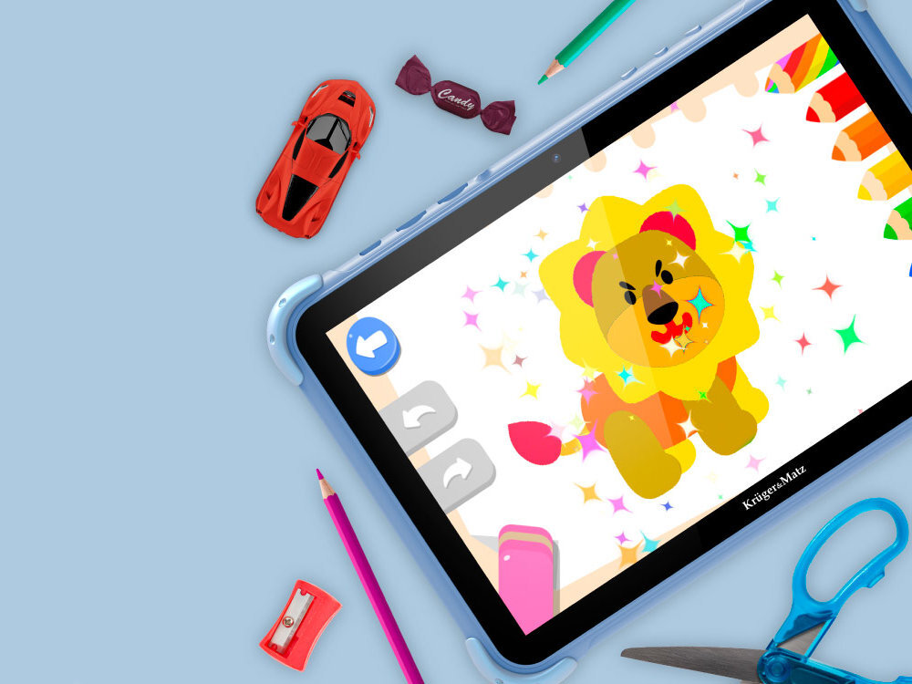 Na obrazie znajduje się tablet Kruger&Matz z kolorową grafiką lwa na ekranie. Wokół tabletu leżą różne przedmioty, takie jak czerwony samochodzik, ołówek, temperówka, nożyczki i cukierek z napisem \'Candy\'.