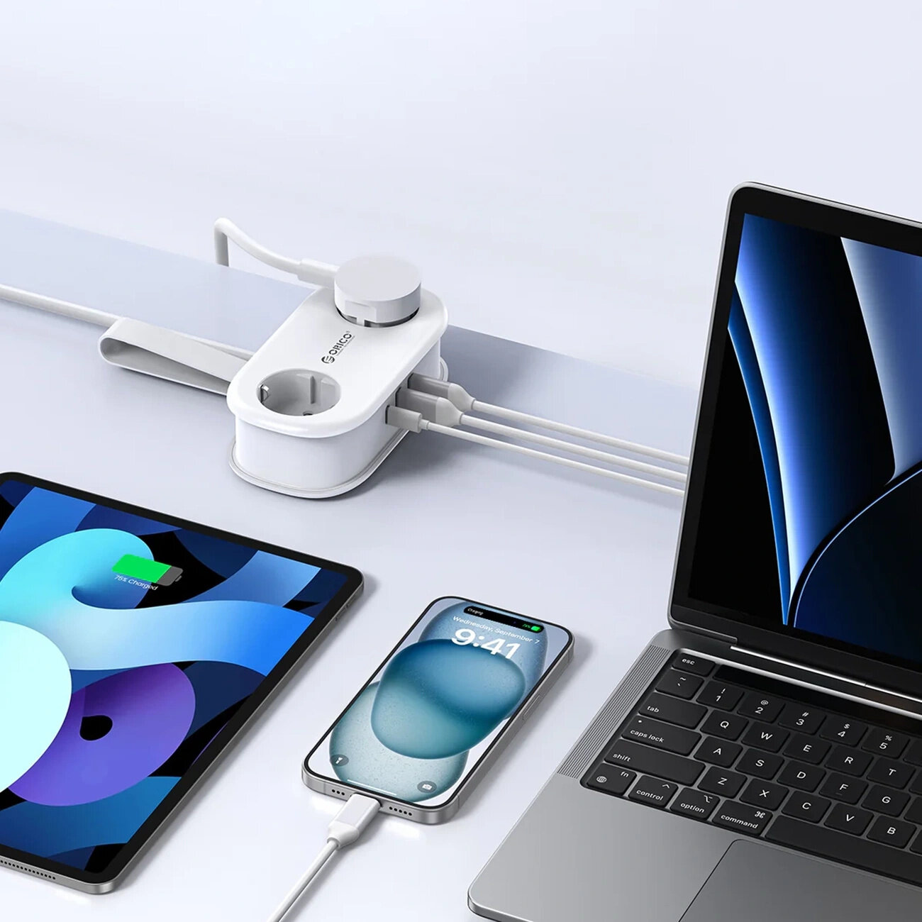 Na obrazie widoczna jest biała listwa zasilająca z logo \'Orico\', do której podłączone są różne urządzenia elektroniczne, w tym laptop, tablet i smartfon. Listwa posiada dwa gniazda AC oraz porty USB-A i USB-C.