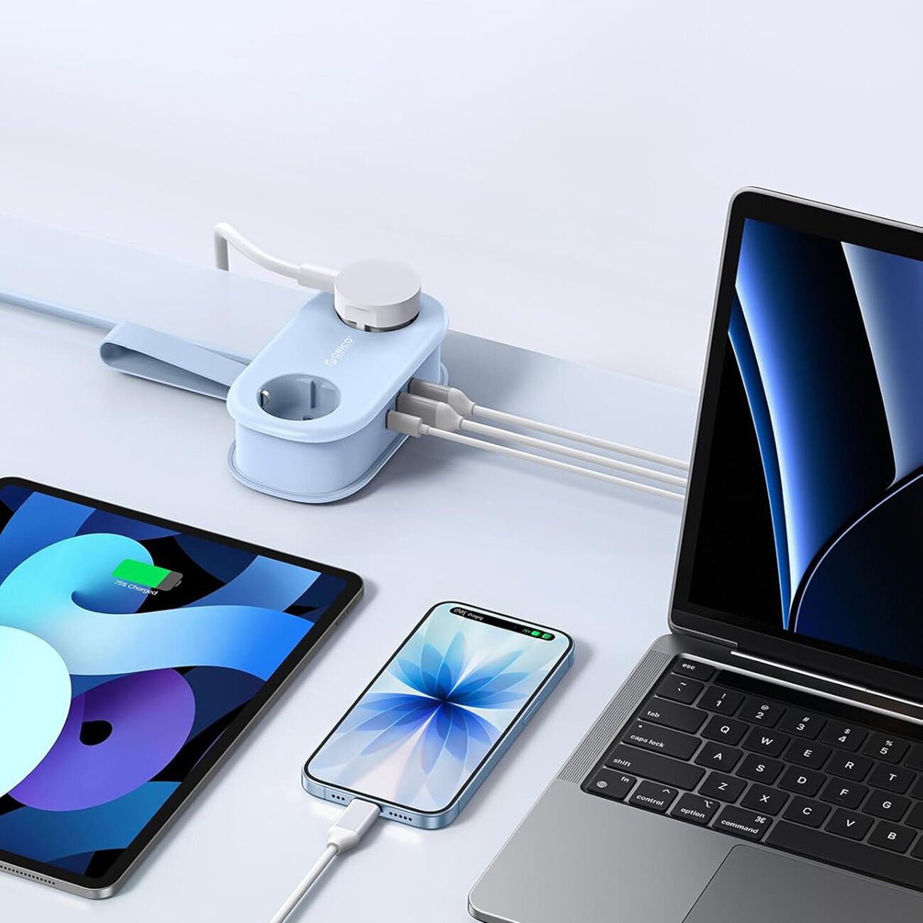 Na obrazie widoczna jest niebieska listwa zasilająca z logo \'Orico\', do której podłączone są różne urządzenia elektroniczne, w tym laptop, tablet i smartfon. Listwa posiada dwa gniazda AC oraz porty USB-A i USB-C.