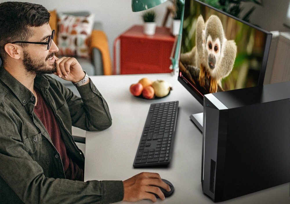 Komputer ACER Aspire XC-1715 TWLD4 Mężczyzna w okularach siedzi przy biurku i patrzy na monitor prezentujący zdjęcie małpy, a po prawej stronie stoi komputer stacjonarny