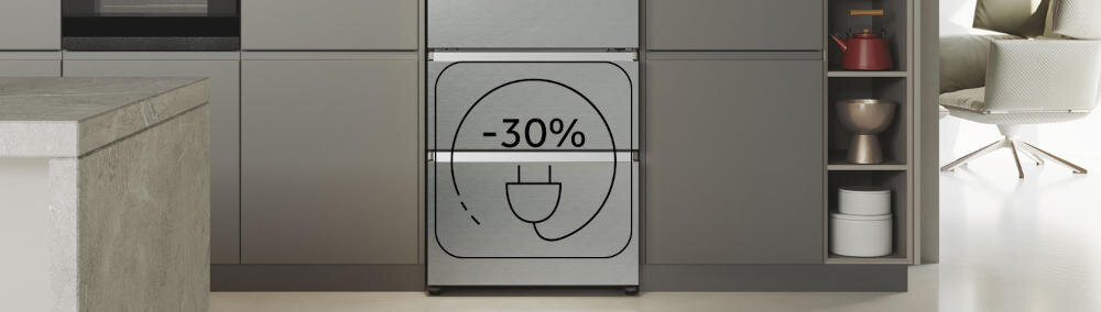 Lodówka w kolorze ciemnego inoxu z napisem \'-30%\' i symbolem wtyczki na drzwiach. W tle widoczna jest nowoczesna kuchnia z szafkami i półkami.