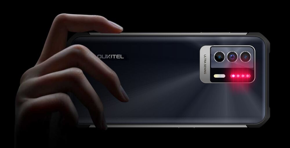 Osoba trzyma czarny smartfon z trzema obiektywami aparatu i napisem \'ULTRA SERIES\'. Na obudowie widoczne jest logo \'OUKITEL\'.