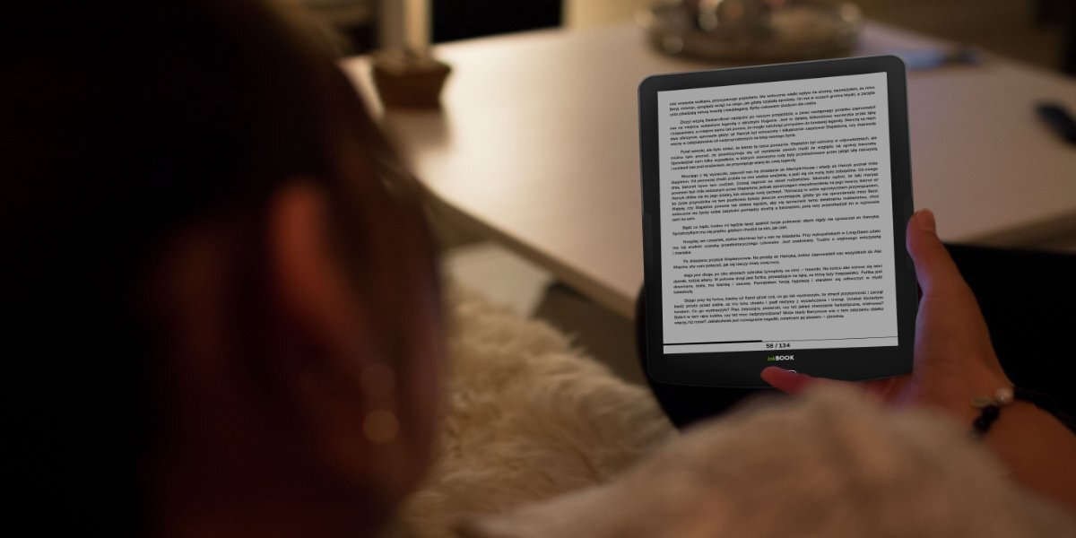 Osoba czytająca książkę na INKBOOK Focus Plus w przyciemnionym pomieszczeniu.