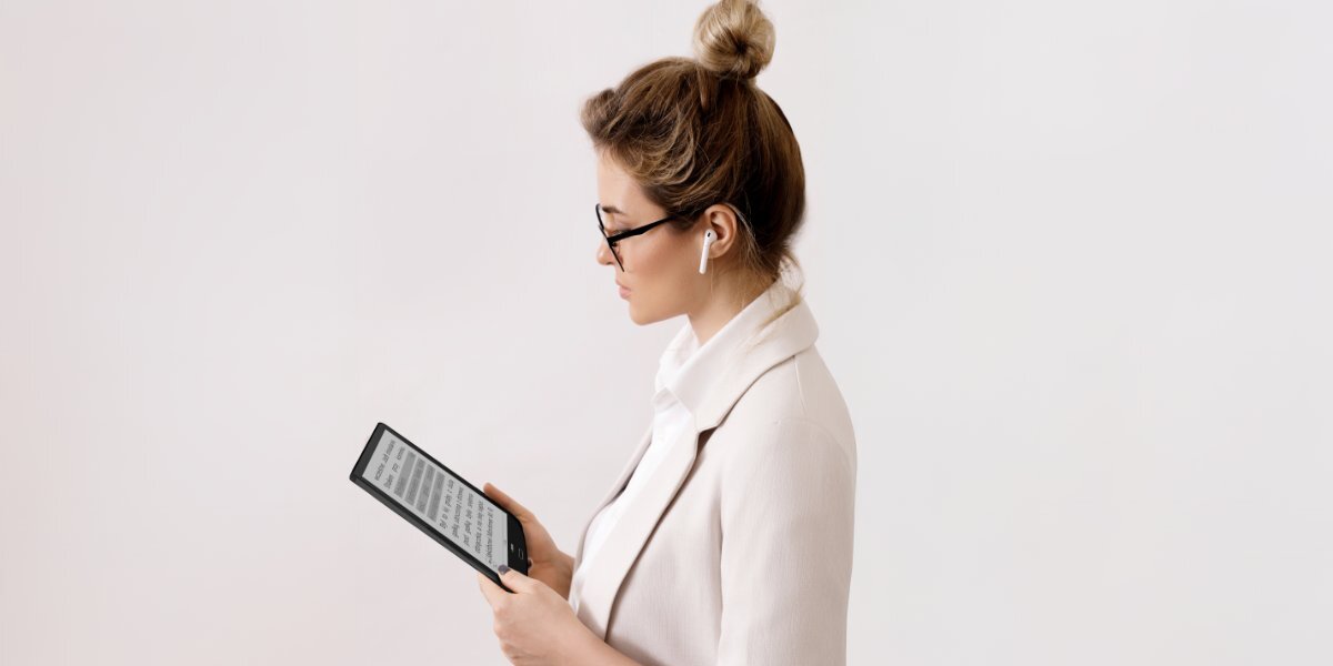 Kobieta używająca INKBOOK Focus Plus na szarym tle.