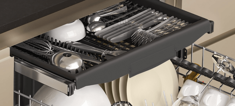 ZMYWARKA WHIRLPOOL WH4ITB14B3N6W Wysunięta górna szuflada na sztućce wypełniona nożami, widelcami, łyżkami i przyborami kuchennymi. Poniżej widoczne są talerze, filiżanki i kieliszki umieszczone w koszach zmywarki trzeci kosz wygodne miejsce na sztućce i drobne akcesoria
