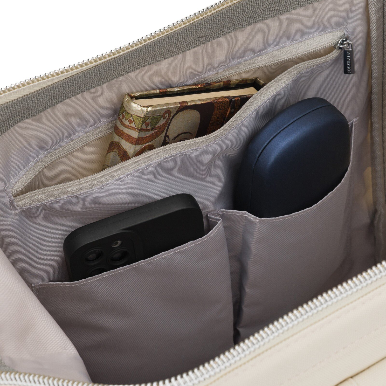 Wnętrze plecaka z kilkoma kieszeniami, w których znajdują się książka, czarne etui na telefon i niebieskie etui. Widać również suwak z napisem \'PETERSON\'.