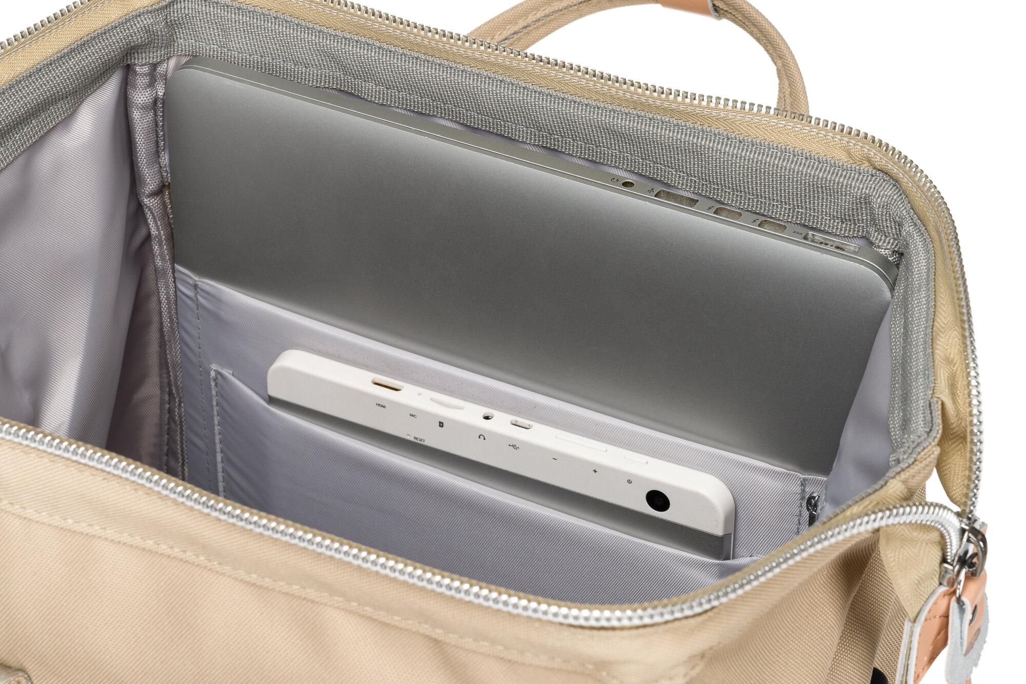 Wnętrze jasnobeżowego plecaka z kieszenią na laptopa, w której znajduje się laptop i tablet. Plecak ma wyściełane wnętrze i zamek błyskawiczny.