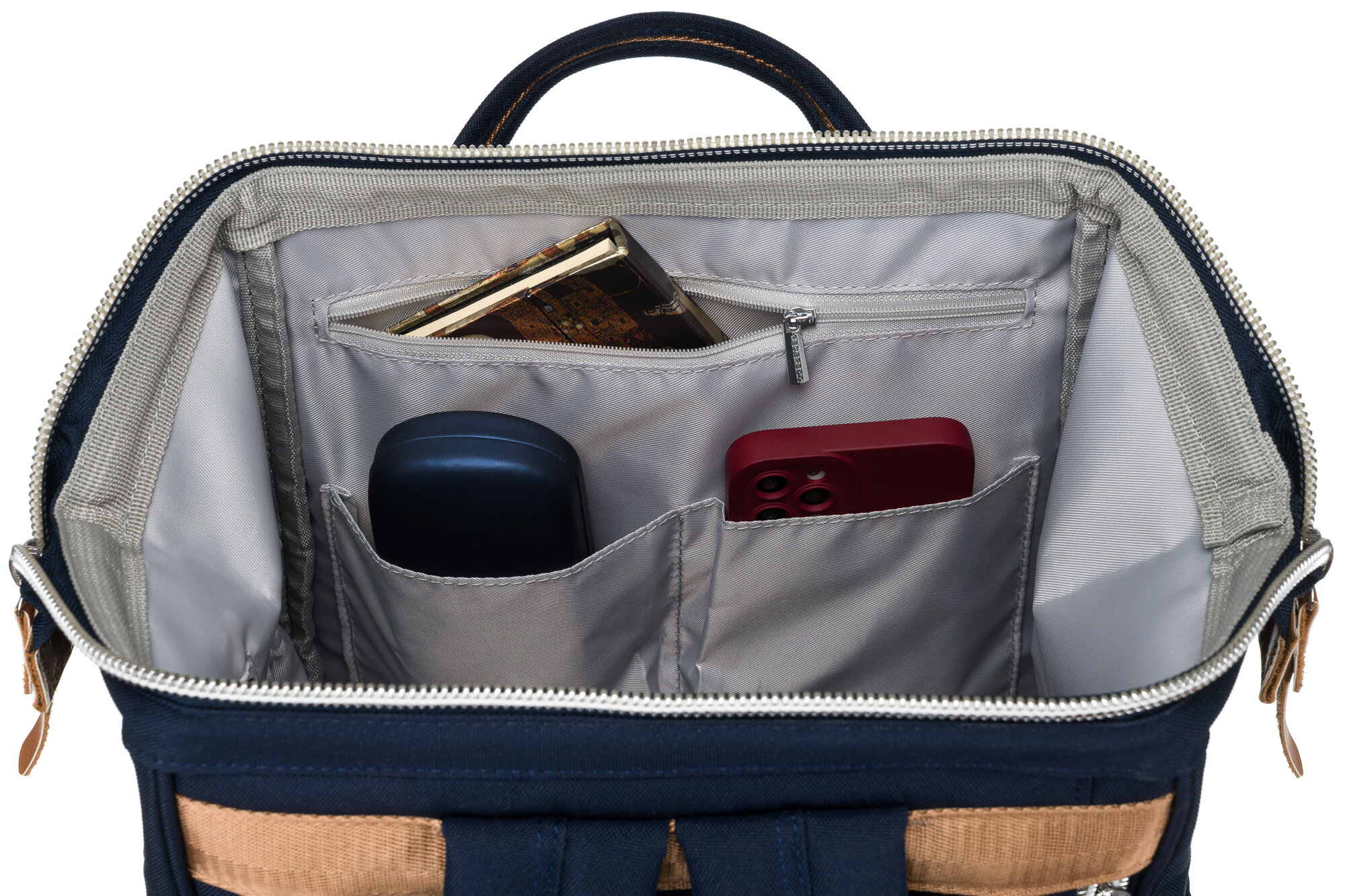 Wnętrze granatowego plecaka z kilkoma kieszeniami, w których znajdują się telefon, okulary i inne drobne przedmioty. Plecak ma jasną podszewkę i zamek błyskawiczny.