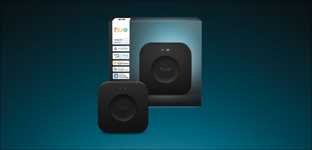 Na obrazie widoczna jest czarna bramka z napisem \'hue\' oraz pudełko z logo \'hue\' i napisami \'Bridge Pro\', \'matter\', \'Zigbee\', \'Apple Home\', \'Google Assistant\', \'Amazon Alexa\'.