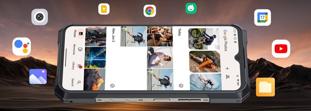 Smartfon z wyświetlaczem prezentującym aplikację Google Photos, otoczony ikonami różnych aplikacji. W tle widoczny jest krajobraz górski o zachodzie słońca.