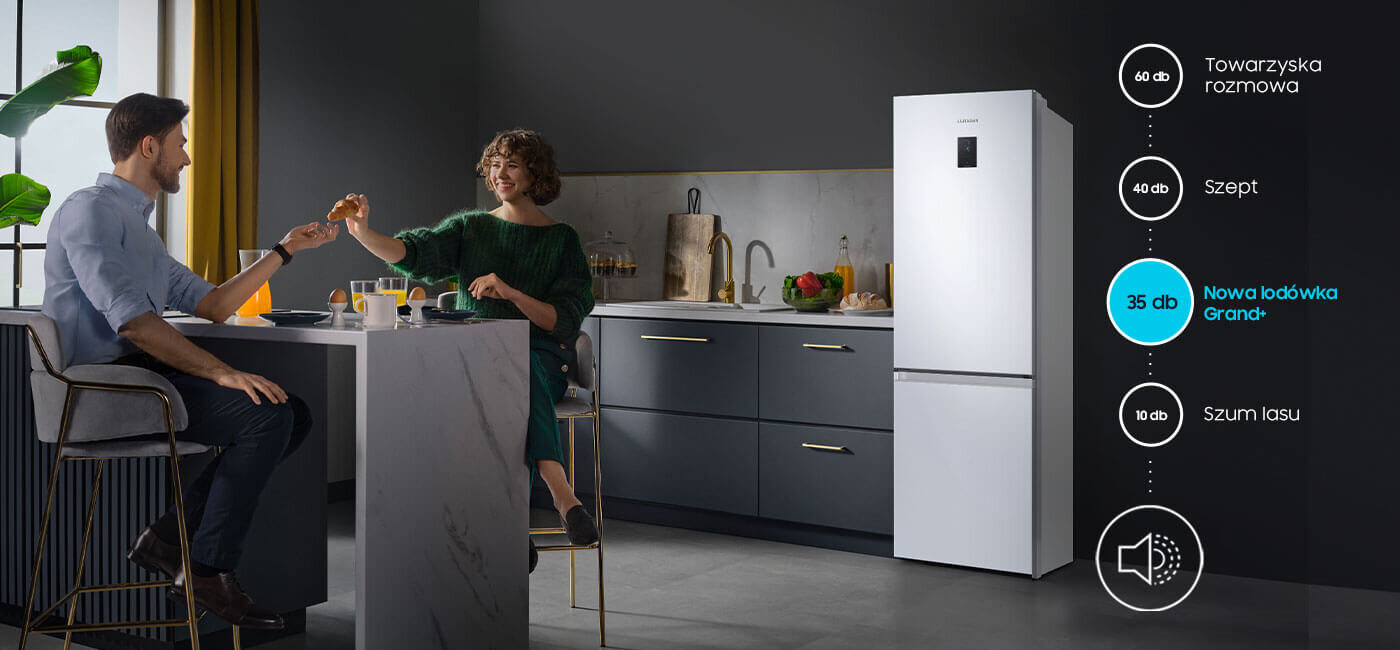 Infografika informuje, że lodówka z dolnym zamrażalnikiem Samsung RB34C675DWW jest niezwykle cicha, działa ciszej nawet od szeptu W kuchni znajduje się biała lodówka obok ciemnych szafek, a po lewej stronie przy stole siedzą dwie osoby. Obok lodówki widoczna jest grafika z poziomami hałasu: 60 dB Towarzyska rozmowa, 40 dB Szept, 35 dB Nowa lodówka Grand+, 10 dB Szum lasu.