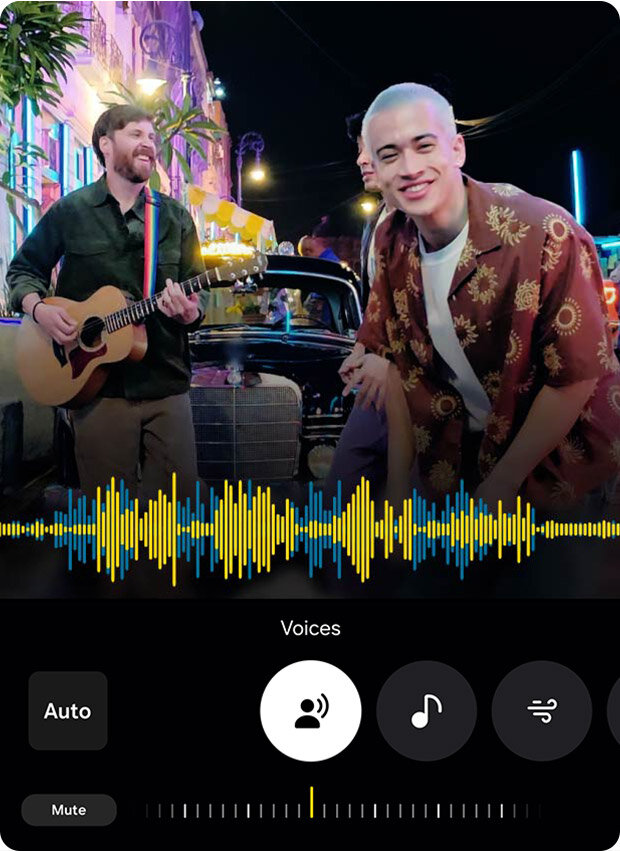Dwóch mężczyzn stoi przed samochodem, jeden z nich gra na gitarze. Na dole ekranu widoczny jest interfejs z napisem \'Voices\' oraz ikonami i wykresem dźwięku.