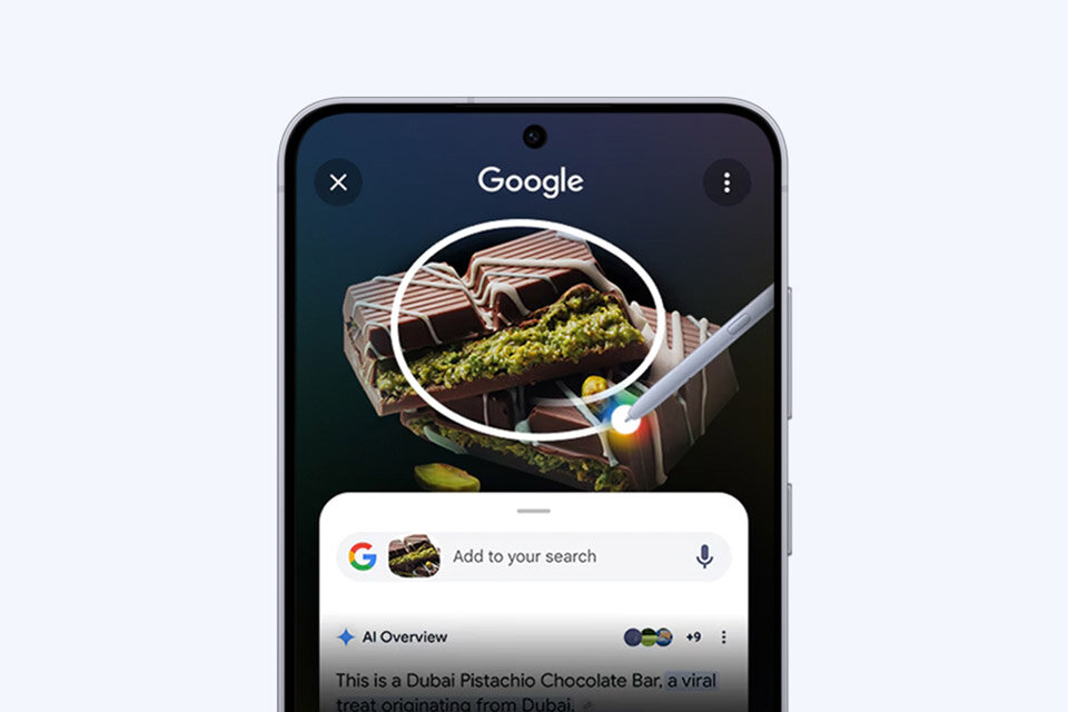 Na ekranie smartfona widoczna jest aplikacja Google z obrazem czekolady pistacjowej oraz narzędziem do zaznaczania. Pod spodem znajduje się pasek wyszukiwania z tekstem \'Add to your search\'.