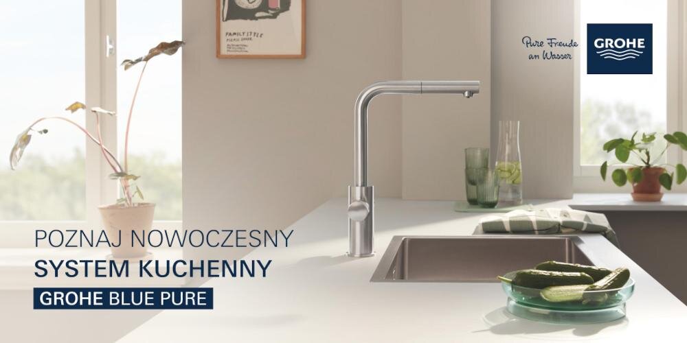 Nowoczesna kuchnia z widoczną baterią kuchenną GROHE Blue Pure na blacie obok zlewu. Na blacie znajdują się ogórki w misce, szklanka z napojem oraz rośliny w doniczkach.