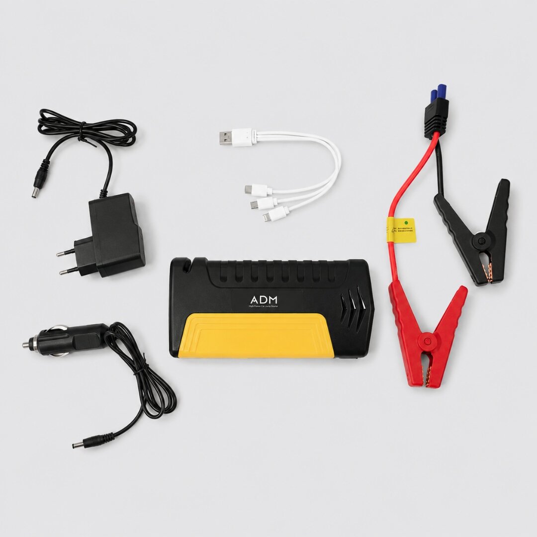 Na obrazie widoczny jest zestaw akcesoriów, w tym wielofunkcyjny rozrusznik samochodowy i powerbank z logo \'ADM\', kable z końcówkami USB, ładowarka sieciowa, ładowarka samochodowa oraz przewody z zaciskami. Wszystkie elementy są rozłożone na jasnym tle.
