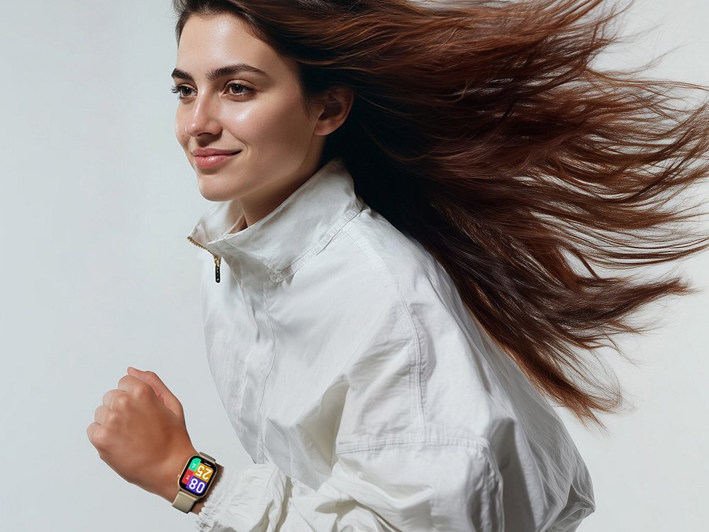 Osoba ubrana w białą kurtkę biegnie, mając na nadgarstku smartwatch z kolorowym wyświetlaczem. Włosy osoby są rozwiane, a tło jest jednolite i jasne.