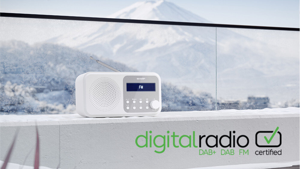 Na tle ośnieżonego krajobrazu znajduje się białe radio z wyświetlaczem pokazującym \'FM\'. W prawym dolnym rogu widnieje napis \'digital radio DAB+ DAB FM certified\'.