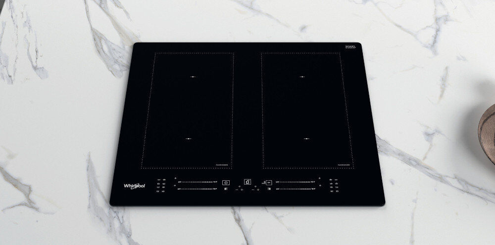 Czarna płyta indukcyjna z dwoma prostokątnymi strefami grzewczymi, widoczne logo \'Whirlpool\' i panel sterowania z ikonami dotykowymi. Płyta znajduje się na marmurowym blacie.