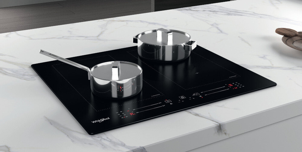 Czarna płyta indukcyjna z dwoma garnkami na blacie kuchennym. Widoczne logo: Whirlpool.