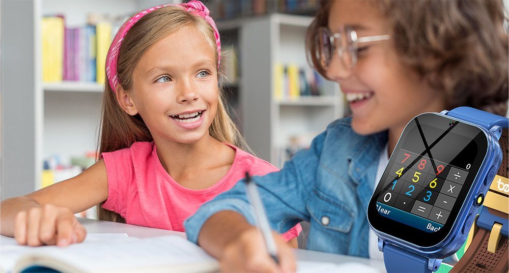 Dwoje dzieci siedzi przy stole, jedno z nich pisze w zeszycie. Na pierwszym planie widoczny jest smartwatch z kolorowym wyświetlaczem, na którym widać cyfry i symbole matematyczne.