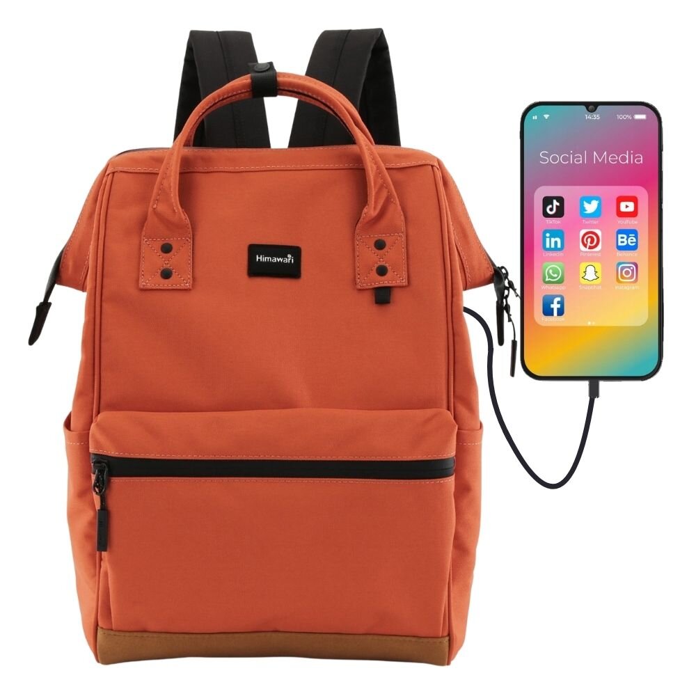 Plecak w kolorze dyniowym z czarnymi elementami, posiada logo \'Himawari\' na przedniej kieszeni. Obok plecaka widoczny jest smartfon z ikonami aplikacji społecznościowych, podłączony do plecaka kablem.