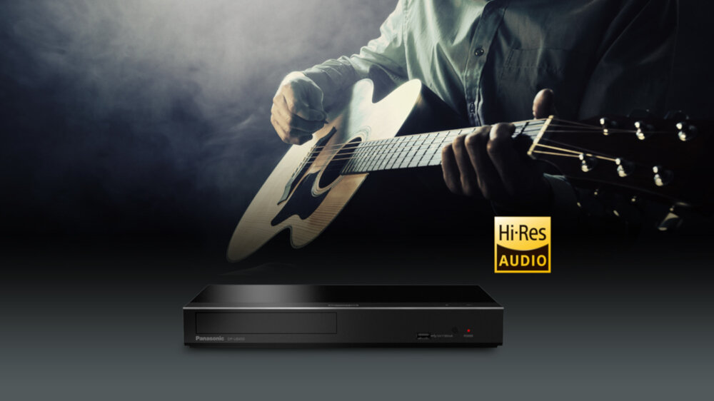 Na obrazie widoczny jest odtwarzacz Blu-Ray z logo Panasonic oraz napis \'Hi-Res Audio\'. W tle osoba gra na gitarze akustycznej.