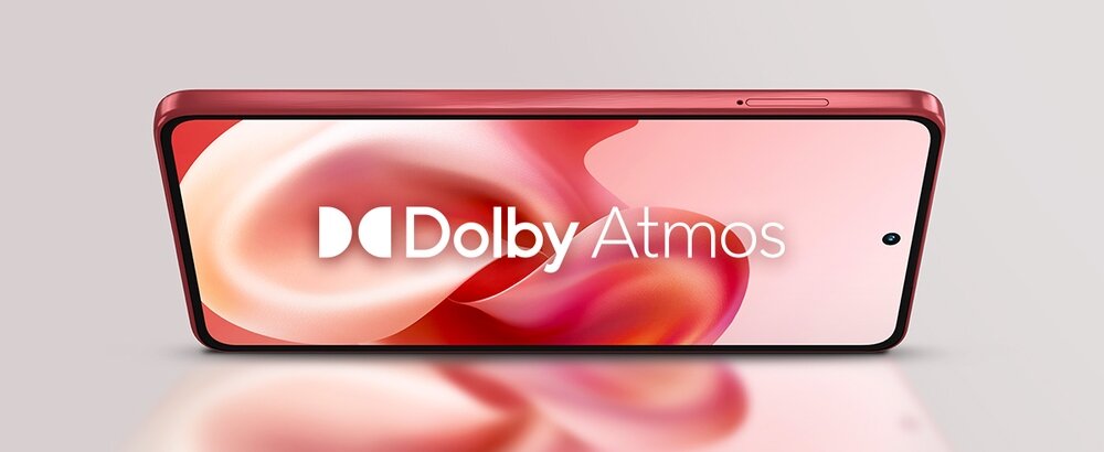 Smartfon w kolorze czerwonym z wyświetlaczem pokazującym logo \'Dolby Atmos\' na tle abstrakcyjnych, różowych wzorów.