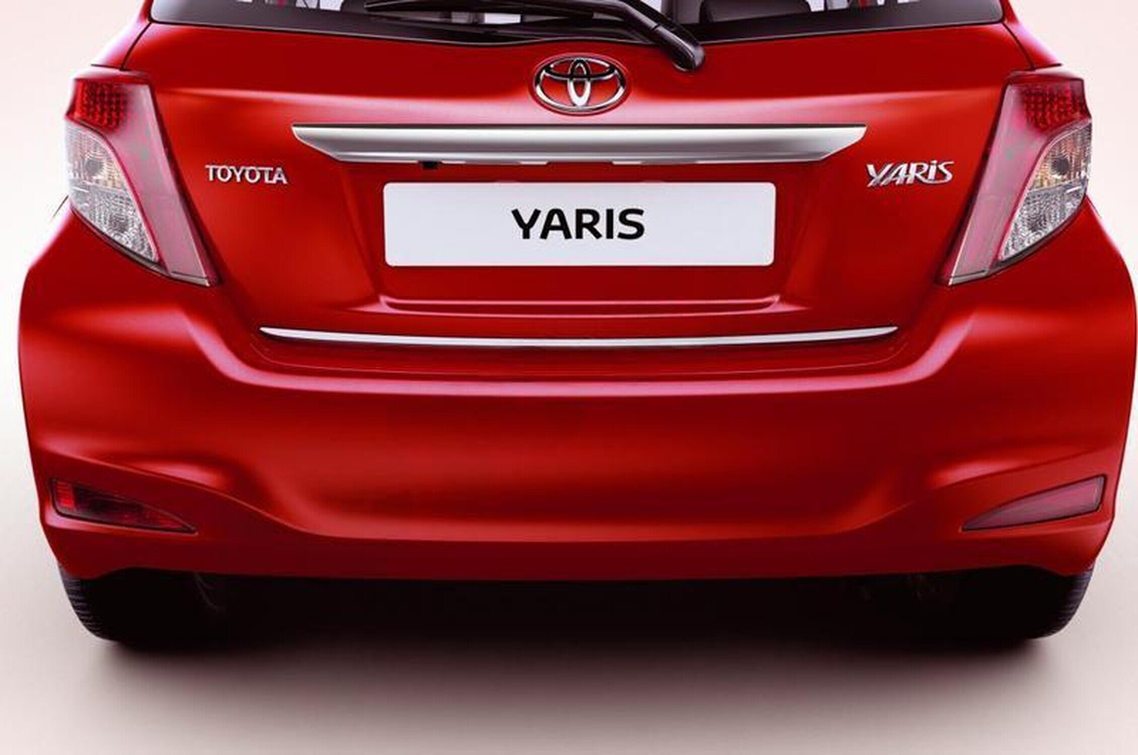 Czerwony tył samochodu z widocznym logo Toyota i napisem Yaris na tablicy rejestracyjnej. Na zderzaku znajduje się srebrna listwa ochronna.