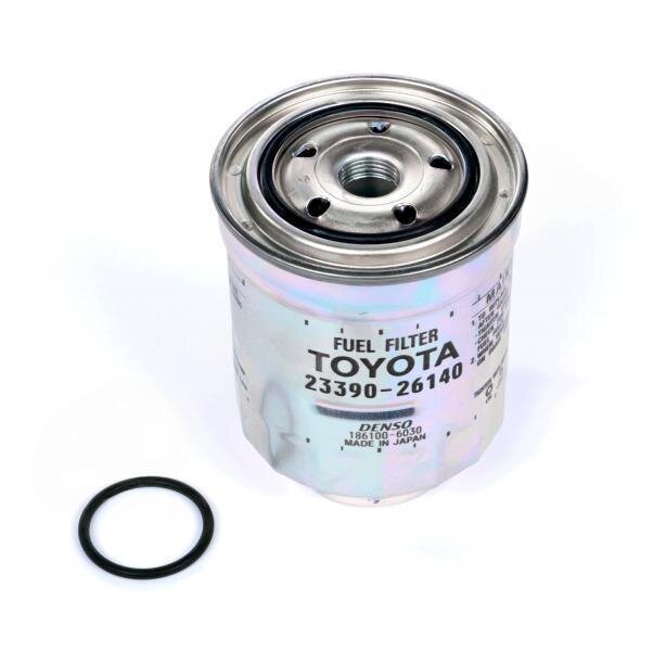 Na obrazie widoczny jest metalowy filtr paliwa z napisem \'FUEL FILTER TOYOTA 23390-26140\' oraz uszczelka obok. Na filtrze znajduje się również napis \'DENSO 186100-5030 MADE IN JAPAN\'.