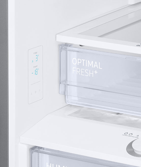Wewnętrzny wyświetlacz w wyposażeniu Wnętrze lodówki z widocznym panelem kontrolnym pokazującym temperatury: Fridge 3°C, Freezer -18°C. Szuflada oznaczona napisem \'OPTIMAL FRESH+\'.