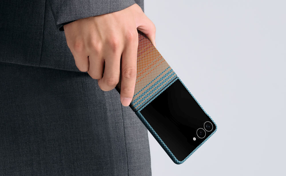 Osoba trzyma telefon w etui o wzorze gradientowym z kolorami pomarańczowym i niebieskim. Telefon ma dwa widoczne obiektywy aparatu i błyszczący ekran.