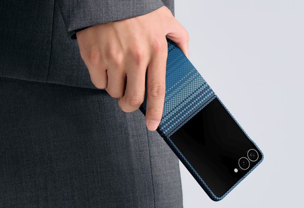 Osoba trzyma telefon w niebieskim etui z widocznymi dwoma aparatami i lampą błyskową. Etui ma wzór przypominający tkaninę.