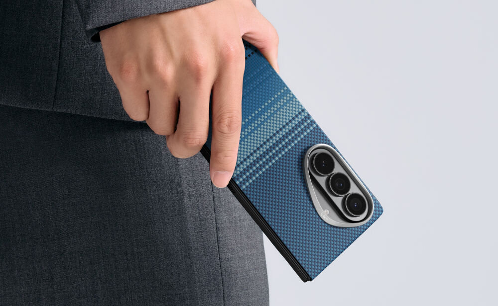 Osoba trzyma telefon w etui o niebieskim wzorze z trzema widocznymi obiektywami aparatu. Etui ma teksturę przypominającą włókno węglowe.