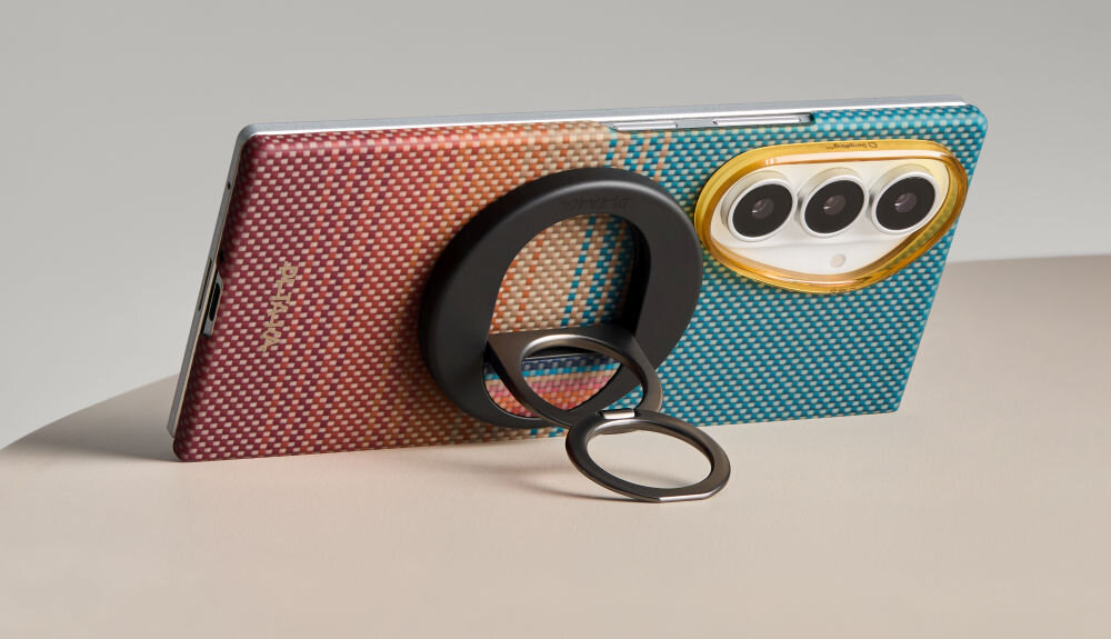 Telefon w etui o wzorze gradientowym z kolorami czerwonymi i niebieskimi, z trzema widocznymi obiektywami aparatu w złotej ramce. Na etui znajduje się napis \'PITAKA\'.