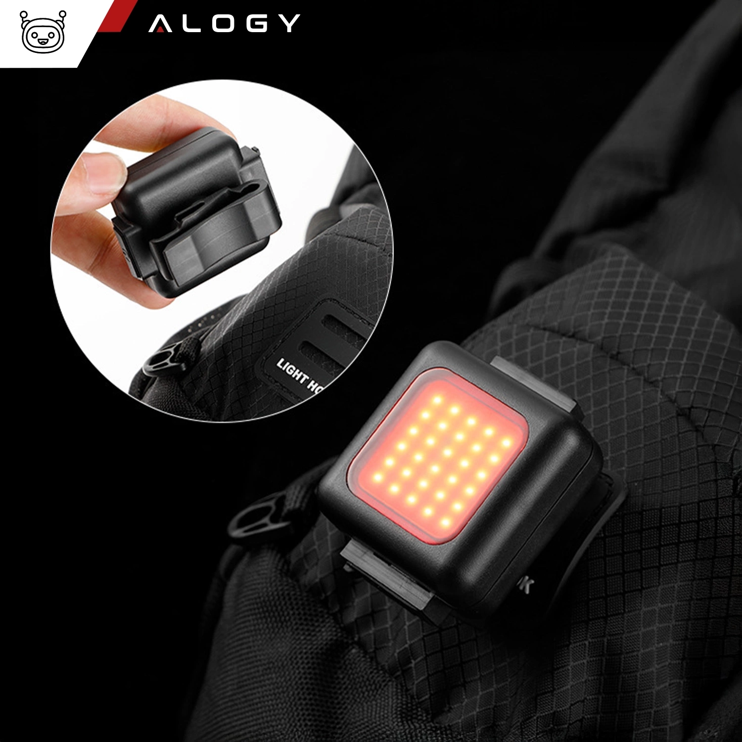Obraz przedstawia czarną lampkę rowerową z czerwonymi diodami LED, zamocowaną na plecaku. W lewym górnym rogu widoczne jest logo \'ALOGY\'.