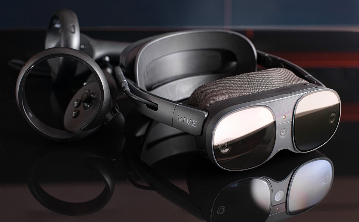 Na obrazie widoczne są gogle VR z napisem \'VIVE\' oraz dwa kontrolery. Gogle mają duże, ciemne soczewki i miękką wyściółkę.