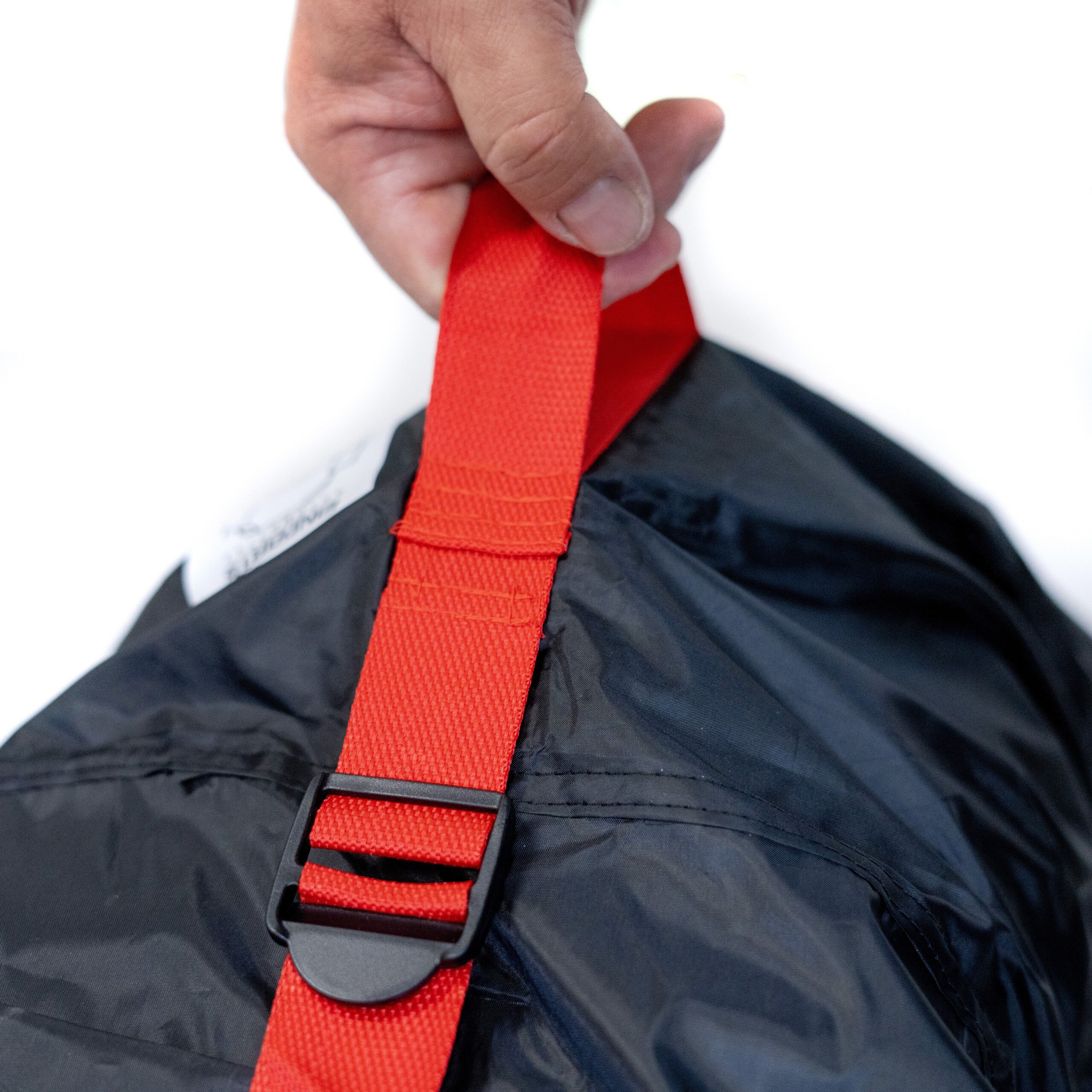 Osoba trzyma czarny materiał z czerwonym paskiem i plastikową klamrą.