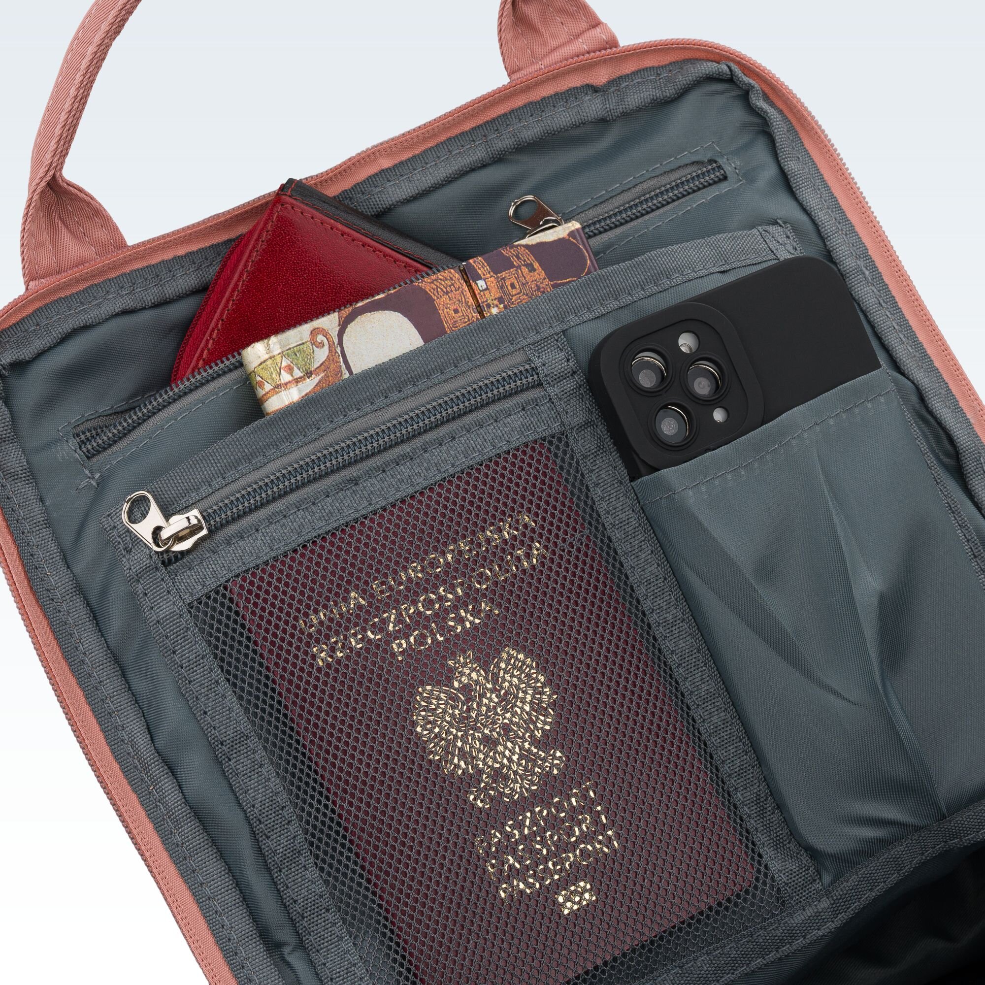 Wnętrze plecaka z kilkoma kieszeniami, w których znajdują się paszport, telefon i portfel. Paszport ma napis \'RZECZPOSPOLITA POLSKA\' oraz godło Polski.