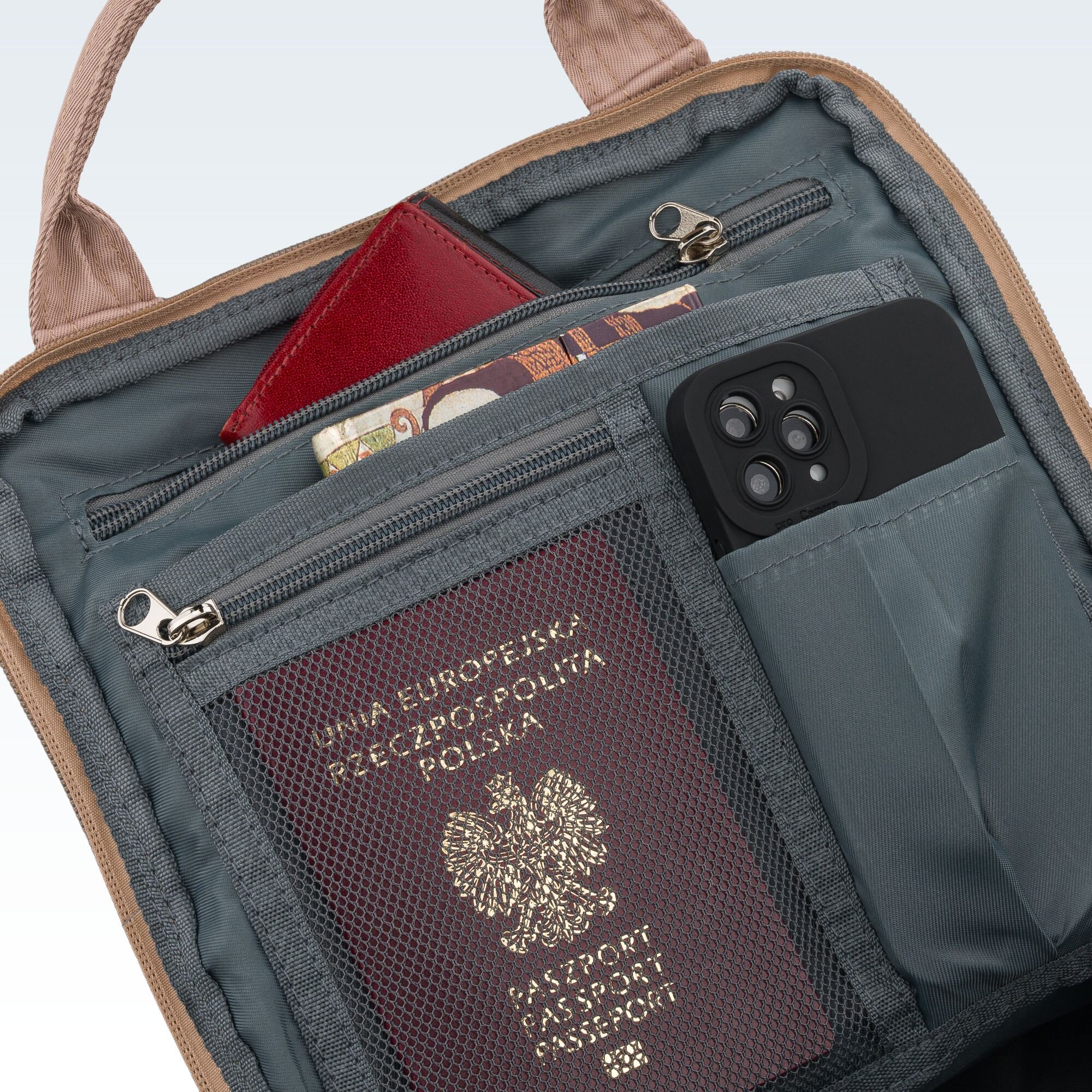 Wnętrze plecaka z kilkoma kieszeniami, w których znajdują się paszport, telefon i portfel. Paszport ma napis \'UNIA EUROPEJSKA RZECZPOSPOLITA POLSKA PASZPORT PASSPORT\'.