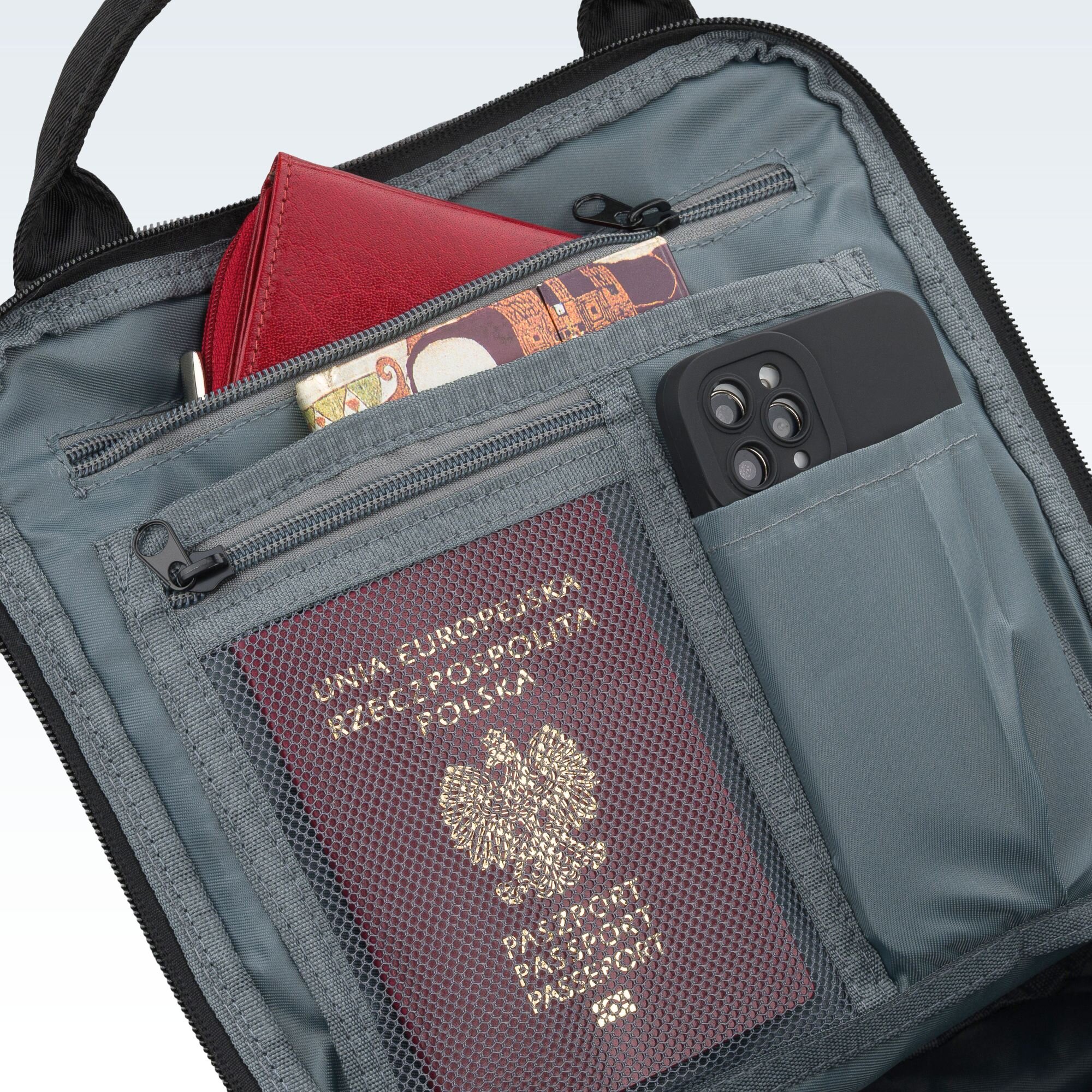 Wnętrze plecaka z kilkoma kieszeniami, w których znajdują się czerwony portfel, banknoty, telefon oraz paszport z napisem \'UNIA EUROPEJSKA RZECZPOSPOLITA POLSKA PASZPORT\'.