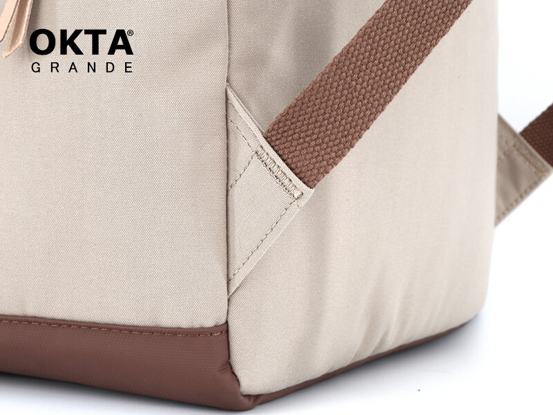 Fragment plecaka w kolorze beżowym z brązowymi elementami, widoczne logo \'OKTA GRANDE\'.