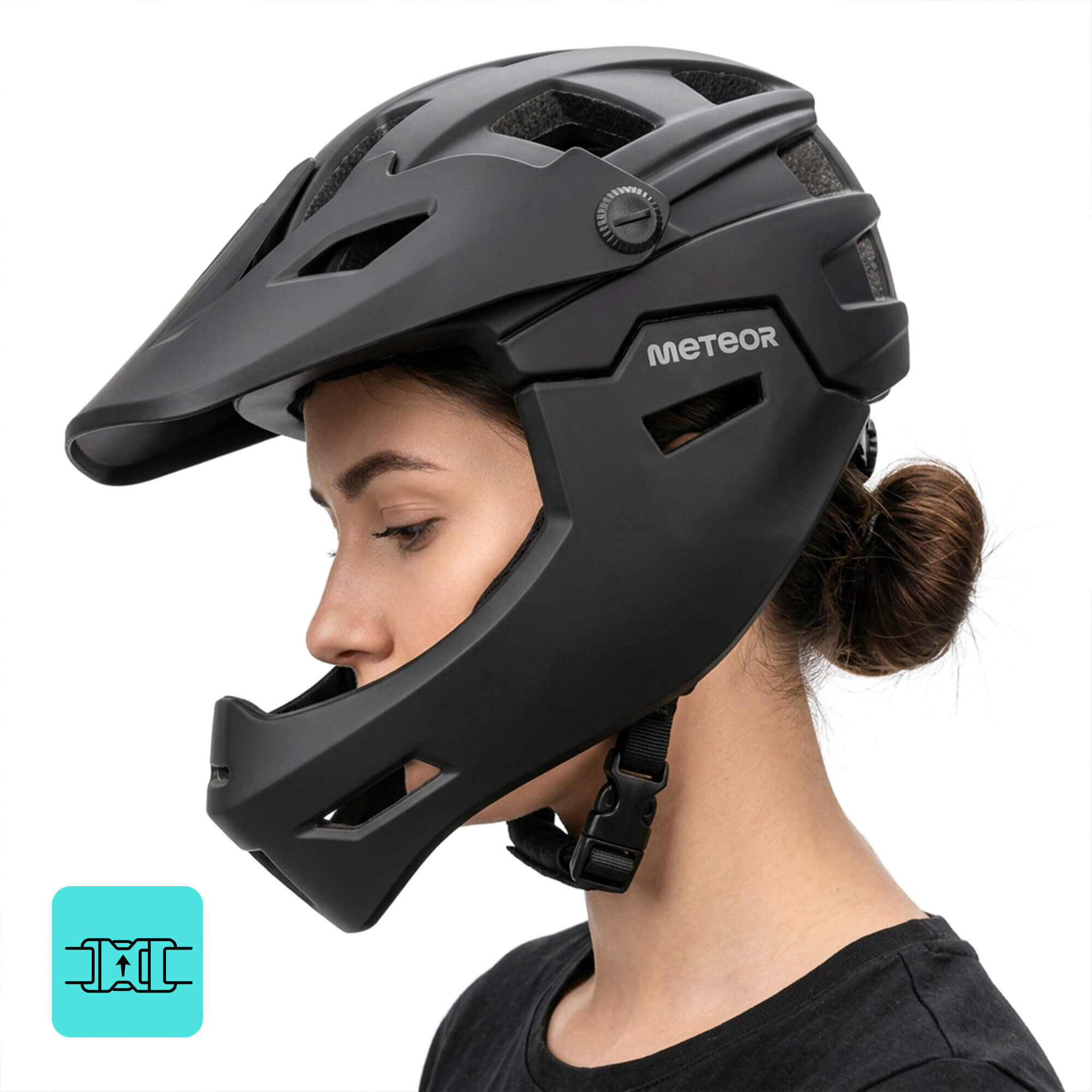 Osoba nosi czarny kask rowerowy full-face z widocznym logo \'METEOR\'. Kask ma otwory wentylacyjne i regulację z boku.