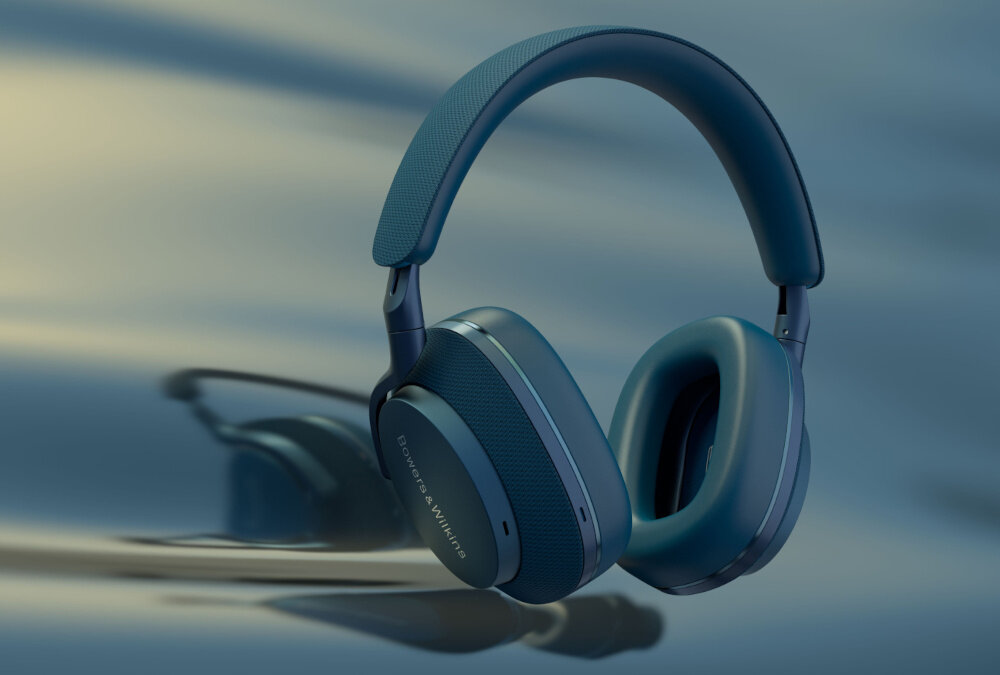 Niebieskie słuchawki nauszne z widocznym logo \'Bowers & Wilkins\' na nauszniku. Tło jest rozmyte, w odcieniach niebieskiego i szarości.