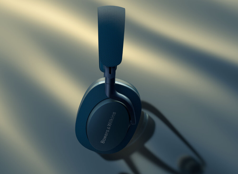 Na obrazie widoczne są niebieskie słuchawki nauszne z napisem \'Bowers & Wilkins\' na nauszniku. Słuchawki mają elegancki design i są oświetlone miękkim światłem.