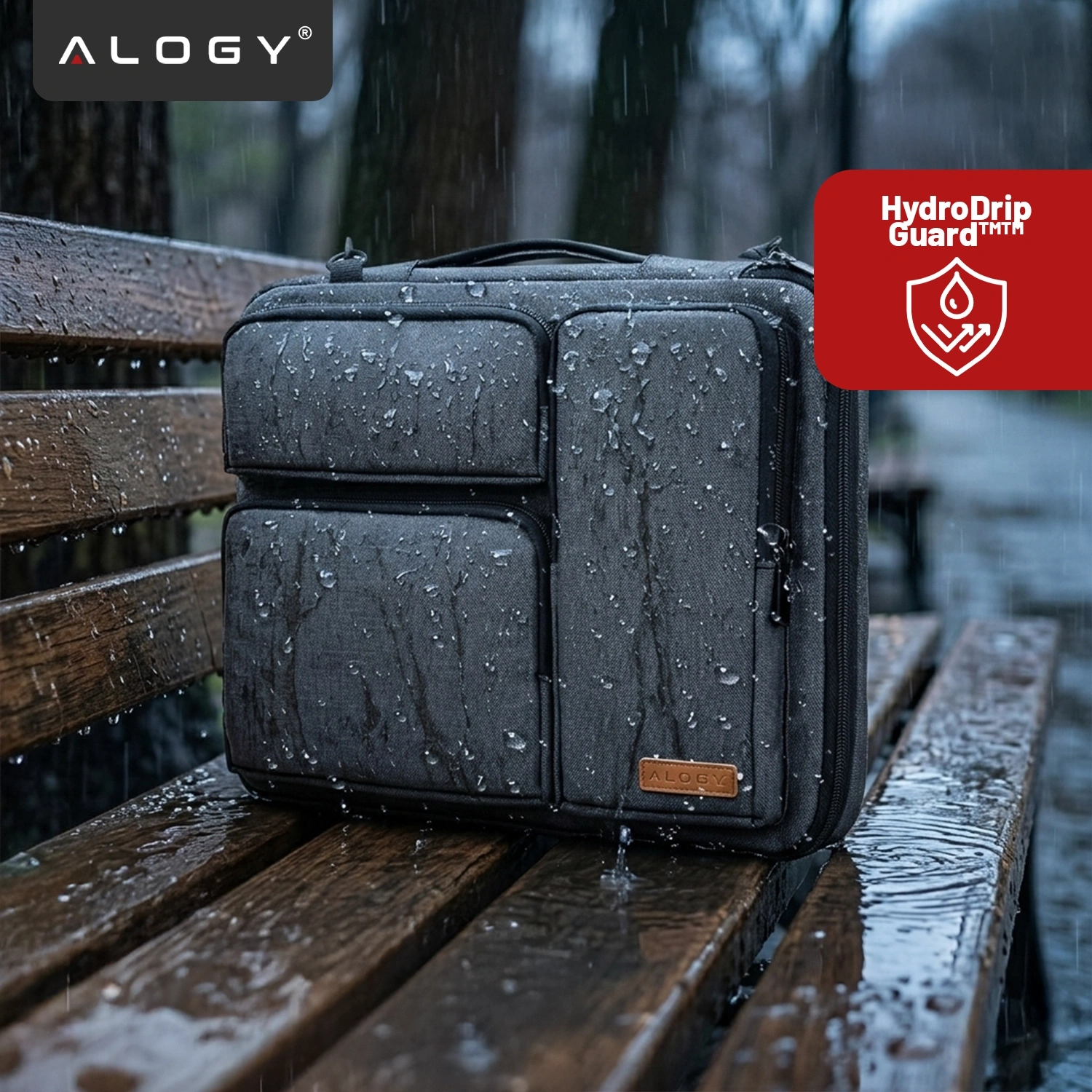 Czarna torba na laptopa z widocznymi kroplami deszczu, umieszczona na drewnianej ławce. W lewym górnym rogu widoczne jest logo \'ALOGY\', a w prawym górnym rogu czerwony znak \'HydroDrip Guard™\' z ikoną kropli wody.