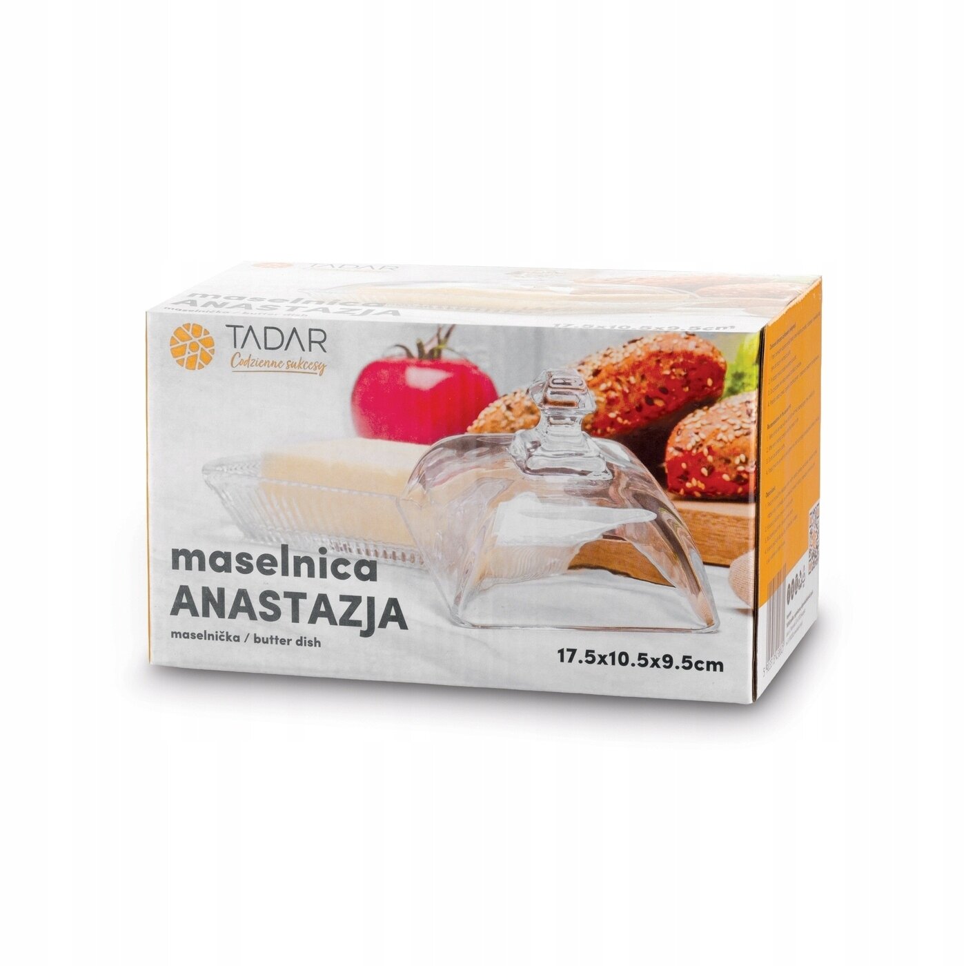 Opakowanie maselniczki szklanej z napisem \'maselnica ANASTAZJA\' oraz logo \'TADAR Codzienna radość\'. W tle widoczne są pomidor i bułki z ziarnami.