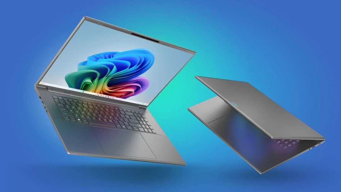 Dwa laptopy w kolorze srebrnym na niebieskim tle, jeden otwarty z widocznym ekranem i klawiaturą, drugi zamknięty. Na ekranie otwartego laptopa widoczny jest kolorowy wzór przypominający logo systemu Windows.