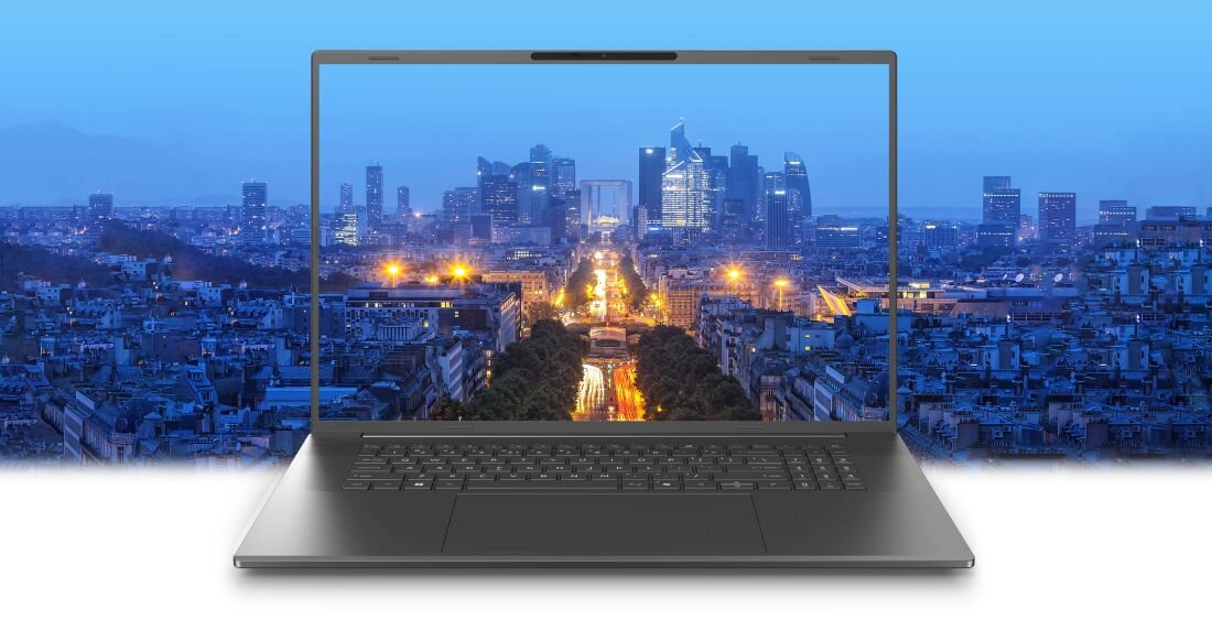 Laptop z dużym ekranem wyświetlającym nocny widok miasta z oświetlonymi budynkami i ulicami. Obudowa laptopa jest w ciemnym kolorze.