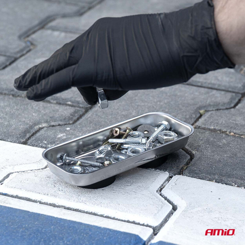 Osoba w czarnej rękawiczce trzyma metalowy element nad podłużną, metalową miską magnetyczną wypełnioną śrubami i nakrętkami. Na dole obrazu widoczne jest logo \'AMiO\'.